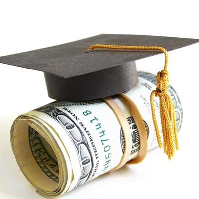 Graduation cap on top of a roll of hundred dollar bills