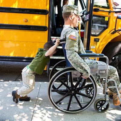 Veteran in a wheelchair being pushed by his son
